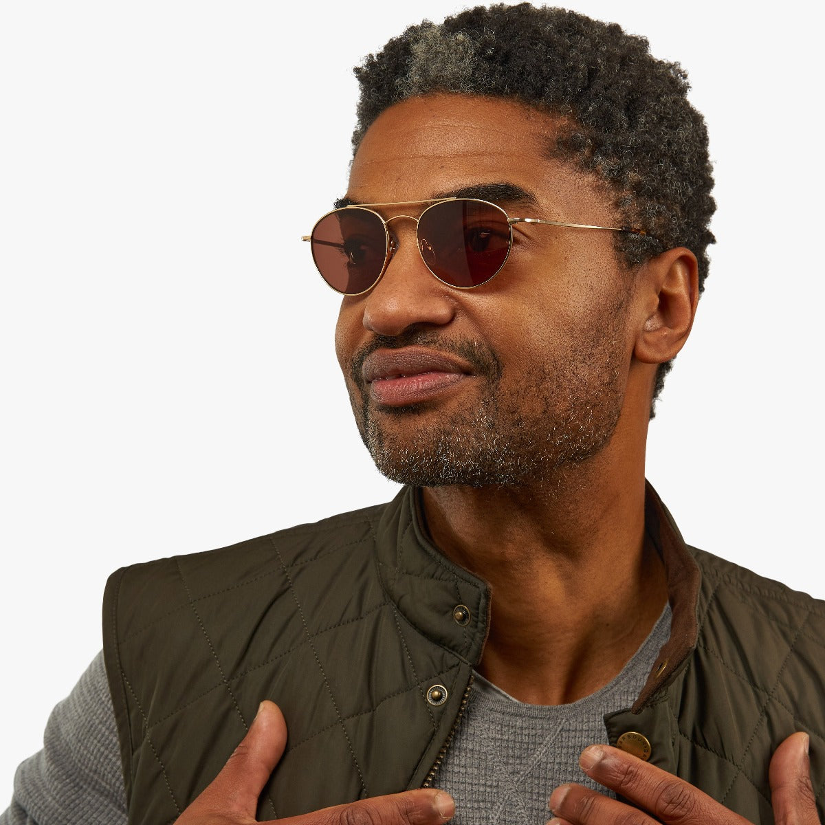 Person wearing round brown tint sunglasses with gold frames